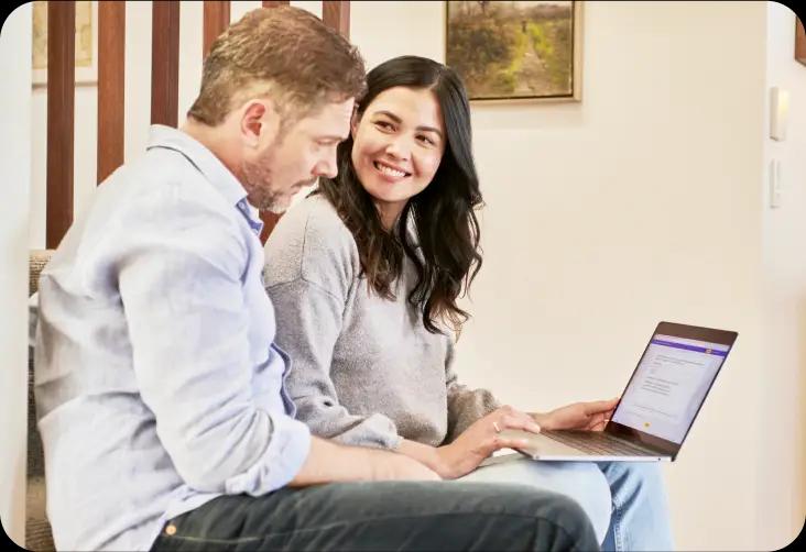 Two people smiling on a laptop